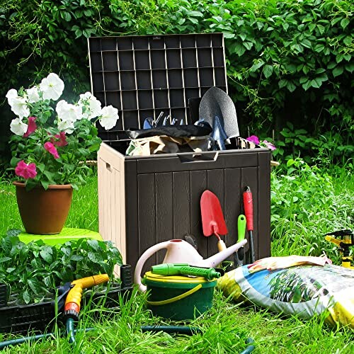 Garden storage box with tools, flowers, and watering can on grass.