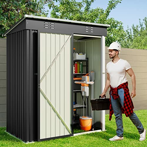 Man carrying toolbox outside small metal storage shed.